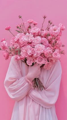 a woman holding a bunch of pink flowers in her hands and covering her face with the fabric