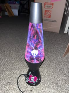 a black and purple lamp with a skull on it's side sitting on the floor