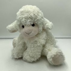 a white stuffed sheep sitting on top of a table next to a wall and floor