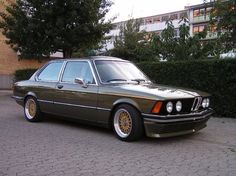 a brown car parked in front of a hedge