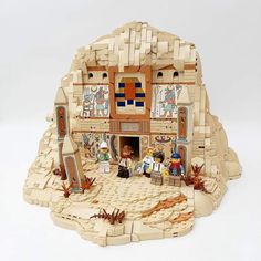 a lego model of a house made out of blocks and bricks with people standing in front of it