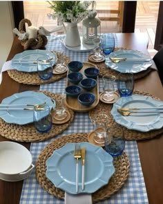 the table is set with blue dishes and place settings