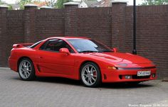 a red sports car parked in front of a brick wall