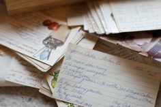 lots of papers are piled on top of each other with pictures and words written on them