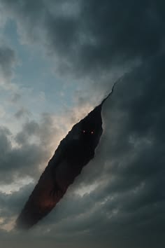 a strange looking object in the sky with dark clouds behind it and an orange glowing eye