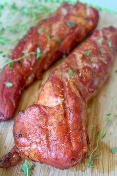 two pieces of meat sitting on top of a wooden cutting board next to each other