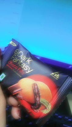 a person holding up a packet of dark chocolate