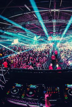 a dj mixing in front of a large crowd at a music festival with bright lights
