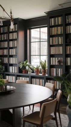 a dining room table with chairs and bookshelves in the background