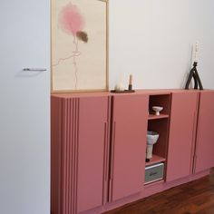 a pink cabinet is next to a painting on the wall