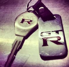 two car keys sitting next to each other on top of a metal surface with the word rr printed on it