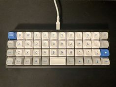 a computer keyboard sitting on top of a black table next to a white and blue key board