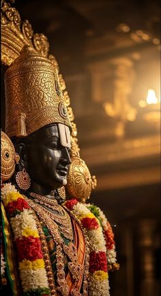the statue is dressed in an elaborate costume and headdress with flowers around his neck