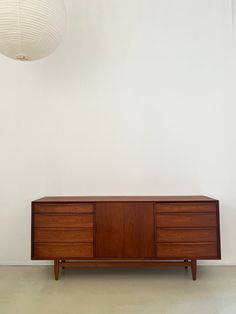 a large wooden cabinet sitting in front of a white wall with a light hanging above it