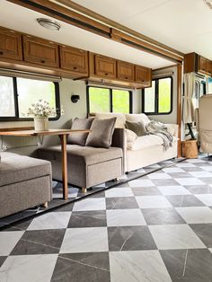 a living area with couches, chairs and windows in an airstream or recreational vehicle