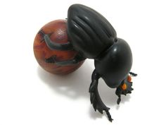 a black and orange beetle sitting on top of an orange ball