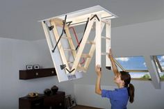 a woman is holding up a light fixture that has been built into the ceiling in her living room