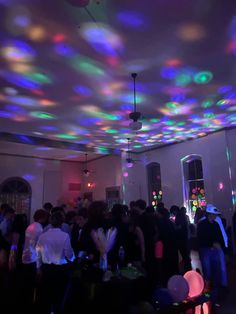 a room filled with lots of people standing around and looking at something on the ceiling