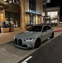 a silver car parked on the side of a road next to a building at night