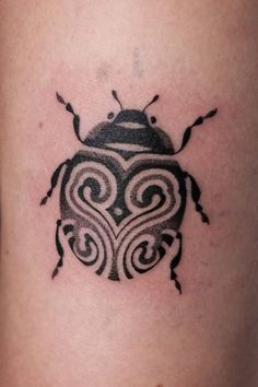 a black and white beetle tattoo on the leg