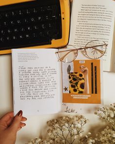 an open book sitting on top of a table next to a typewriter and glasses