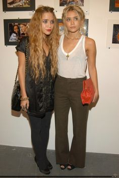 two young women standing next to each other in front of pictures on the wall behind them