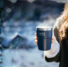 a woman holding a coffee cup with steam coming out of it's top and bottom