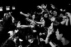 a group of people standing around each other with their arms in the air and one person reaching for something