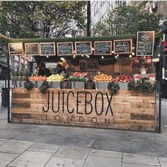 a juice box on london sign in front of a fruit stand with lots of fresh produce