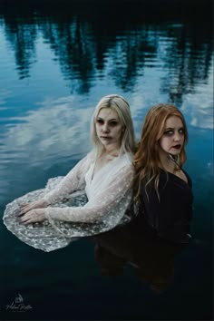 two women are floating in the water with their faces painted white and one is wearing makeup