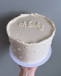 a person holding up a cake with the word oh baby on it in white frosting