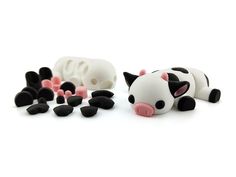 a small toy cow laying on top of some black and white pieces with pink noses