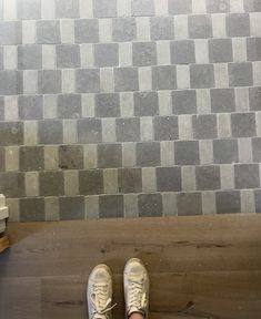 a pair of shoes sitting on top of a wooden floor next to a tiled wall