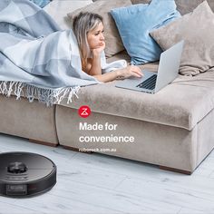 a woman laying on a couch under a blanket with a laptop in front of her