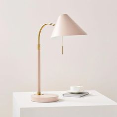 a white table with a pink lamp on it and a phone sitting next to it