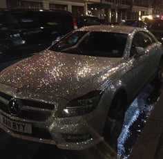 a silver car parked on the side of a street next to tall buildings at night