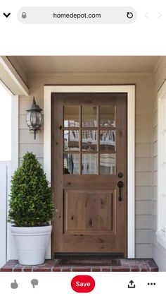 a wooden door on the side of a house with potted plants in front of it