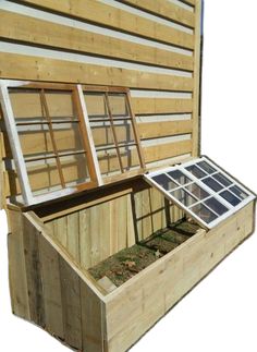 an open wooden box with windows on the outside and grass growing inside it, against a white background