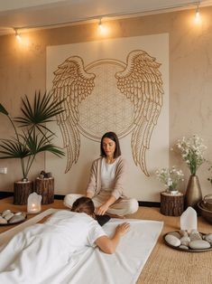a woman getting a back massage from a man in front of a wall with angel wings on it