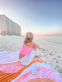 a woman sitting on top of a beach next to the ocean