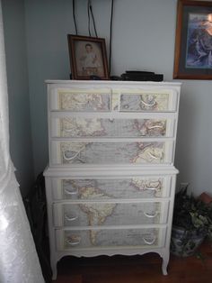 a white dresser with maps on the drawers
