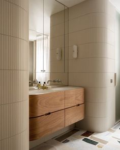 a bathroom with two sinks, mirrors and tiled flooring in beige tones on the walls