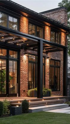 Modern brick house with large windows and illuminated terrace in the evening.