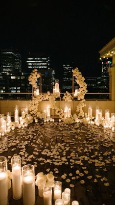 candles and flowers are arranged on the floor in front of cityscape at night