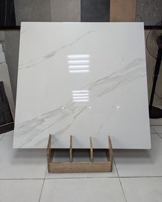 a large white marble slab sitting on top of a tile floor next to a wooden stand