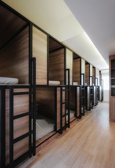 a long row of bunk beds in a room with hard wood flooring and walls