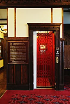 a red door is open in an old building with wood paneling and ornate carvings