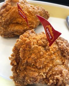 two pieces of fried chicken on a plate with a red flag sticking out of it