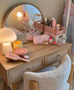 a vanity with a mirror, lamp and various items on it in front of a bed