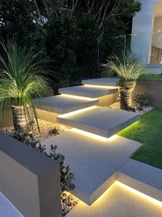 an outdoor garden with concrete steps lit up by led lights and grass in the background